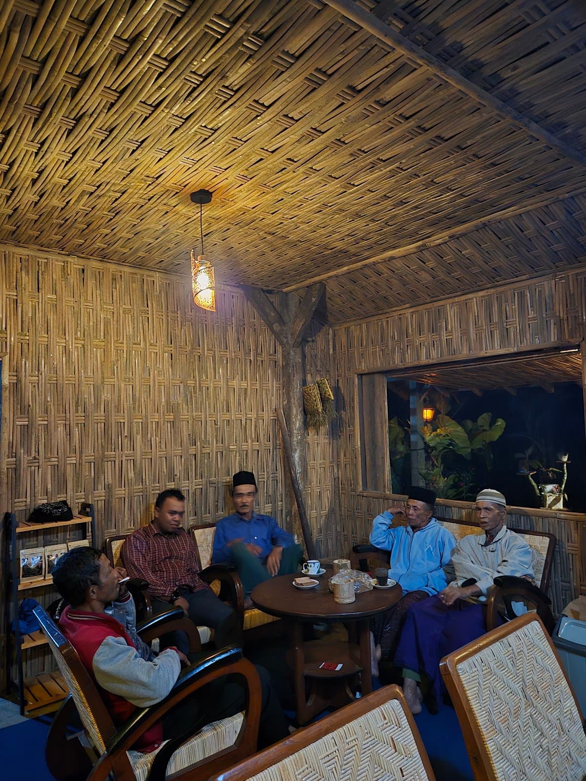 Warga Kampung Aren Simacan mengobrol di kursi rotan Tepi Hutan Café